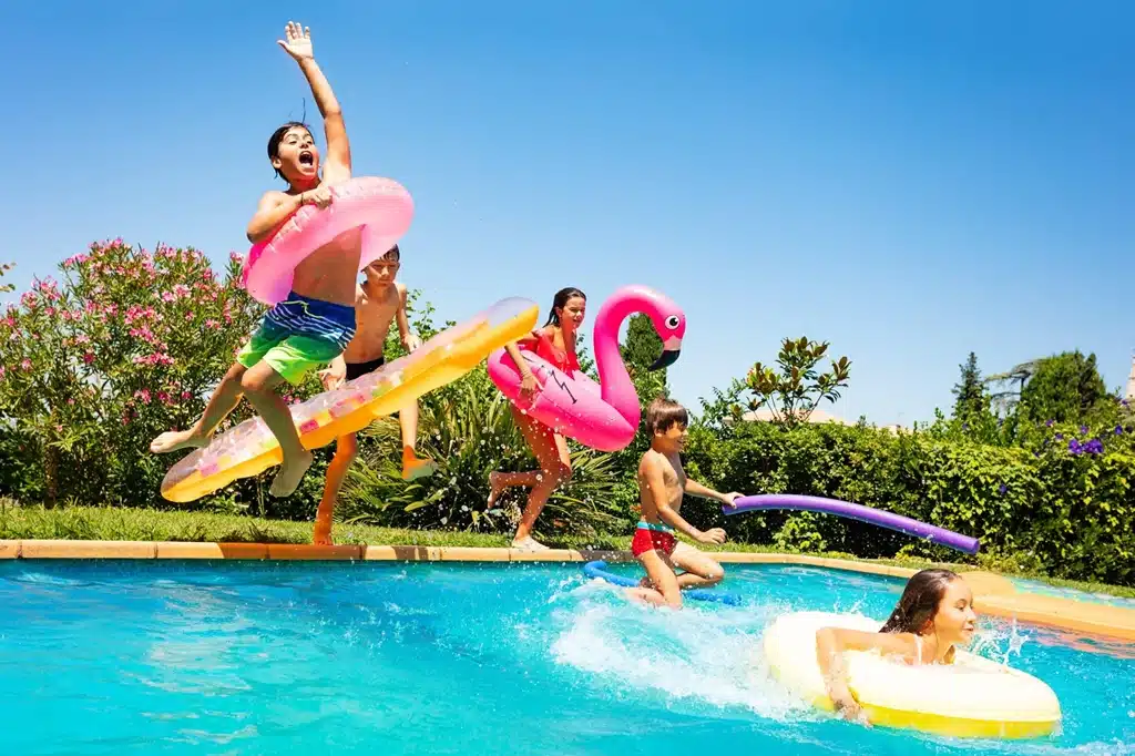 children jumping into the pool with inflatable balls